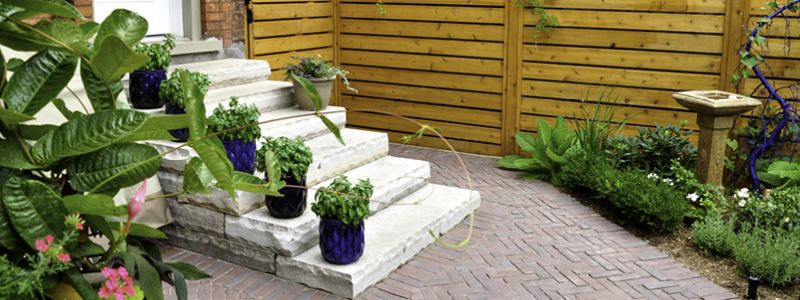 brick patio with concrete steps and potted plants on each step