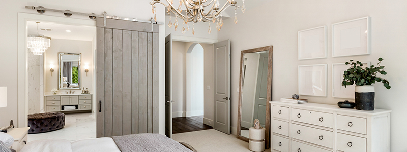 image of contemporary styled bedroom with single barn door installed as door for bathroom