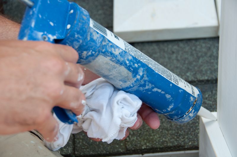 hands holding a caulk gun applying caulk to a joint